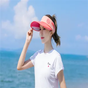 Damen Sonnenvisier in Rosa, getragen von einem Model an einem sonnigen Strandabschnitt.