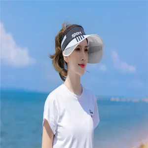 Asiatisches Modell am Strand mit einer schwarz-weißen Sonnenblende für optimalen Sonnenschutz