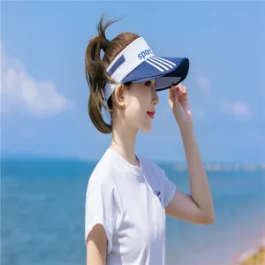 Seitenansicht einer asiatischen Frau mit blau-weißem Sport-Sonnenvisier am Strand