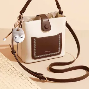 Dettaglio di un simpatico ciondolo Mu Yu in vinile bianco appeso a una borsa chic