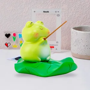 Detailed macro view of a cute frog figurine incense burner holding a stick on a lotus leaf