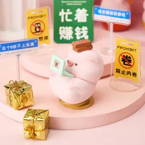 Close-up of pink pig figurine desk ornament with mini laptop and props