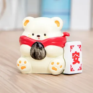 Primer plano de una figura de oso blanco con bufanda roja y ficha decorativa Mahjong