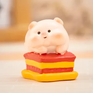 Primer plano de una tierna figura de cerdito de resina sentada sobre un pastel.