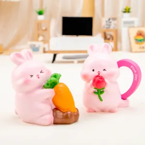 Detailed view of two cute pink resin rabbit figurines holding a carrot and a rose.