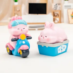 Two cute pink resin rabbit figurines: one riding a blue scooter and one resting on a scale.