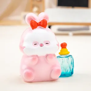Detail view of a pink resin rabbit figurine with a red bow and blue bottle