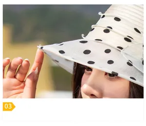 Close-up detail of white organza sun hat with black polka dots and fine mesh texture.