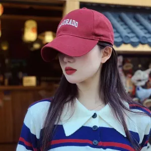 Asiatisches Model mit weinroter bestickter Baseballkappe in trendiger Straßenszene