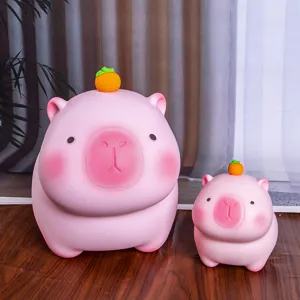 Par de huchas capibara rosas en dos tamaños con pequeñas naranjas en la cabeza.