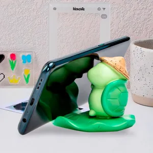 Detailed view of a cute turtle frog phone stand with a straw hat on a green lotus leaf base