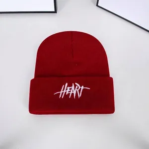 Detailed macro shot of a red knitted beanie with white HEART embroidery for winter wear