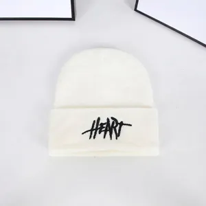 Detailed view of the black HEART embroidery on a white knitted winter beanie hat
