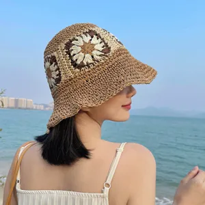 Seitenansicht einer Frau mit einem gehäkelten Strohhut mit Blumenmuster am Strand