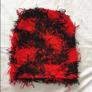 Detailed macro view showing the textured red and black distressed hairy knit beanie hat