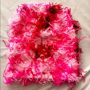 Macro view showing the distressed texture of a pink and red fuzzy knit balaclava