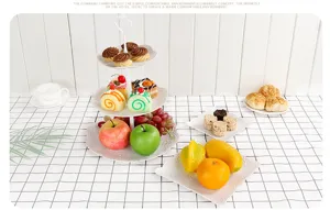 Weißes 3-stöckiges Etagere-Set mit Obsttellern auf einer karierten Tischdecke Szene