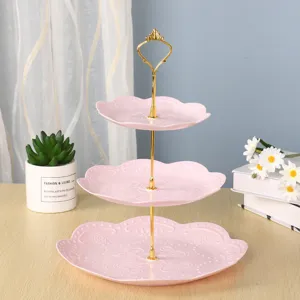 Présentoir à desserts élégant à trois niveaux en plastique rose avec une poignée dorée chic.
