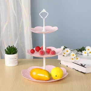 Dreistöckiger rosa Dessertständer mit frischen Früchten und Dekoblumen