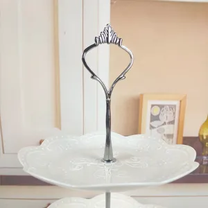 Detailansicht einer weißen Etagere aus Keramik mit einem eleganten silbernen Kronengriff
