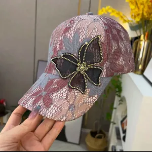 Close-up of a sparkling rhinestone butterfly on a women's pink lace baseball cap