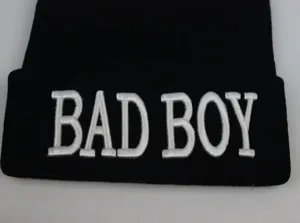 Gros plan d'un bonnet en tricot noir avec texte BAD BOY brodé en 3D de couleur blanche
