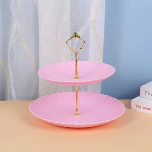 Gros plan d'un présentoir à gâteaux rose à deux niveaux avec poignée en métal doré