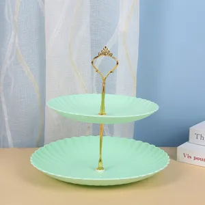 Vue détaillée d'un présentoir à gâteaux vert menthe à deux niveaux avec poignée dorée