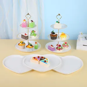Présentoirs à gâteaux étagés et assiettes en cœur pour décoration de table de fête.