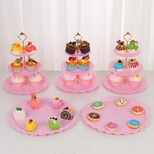 Vue détaillée de supports à gâteaux roses à 3 niveaux et plateaux avec de fausses pâtisseries.