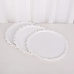 Vue détaillée des plateaux de service décoratifs en plastique blanc aux bords dentelés.