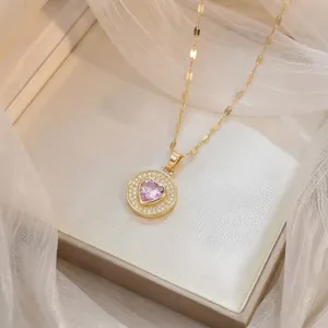Primo piano dettagliato di una collana d'oro con pendente in zircone rosa a forma di cuore.
