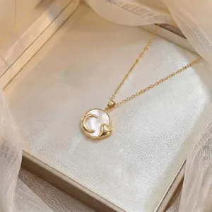 Primo piano del ciondolo della collana dorata con inserto in madreperla, luna e cuore