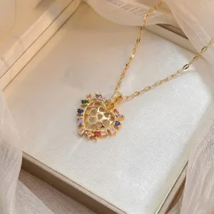 Detalle de cerca de un collar con colgante de corazón dorado y circonitas de colores.