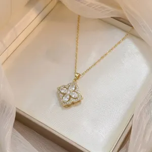 Gros plan d'un pendentif doré à quatre pétales serti de zircons brillants.