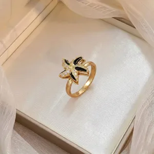 Gold starfish ring with black enamel and sparkling stones shown in a luxurious gift box