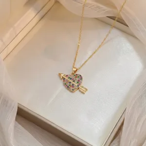 Primer plano del colgante de corazón dorado con circonitas de colores y flecha.