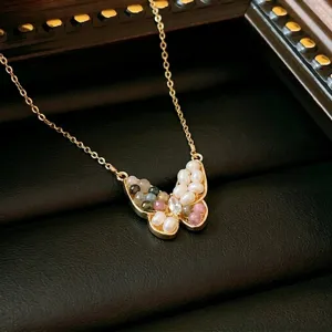 Detailed view of a gold titanium steel butterfly necklace with pearls and gems.