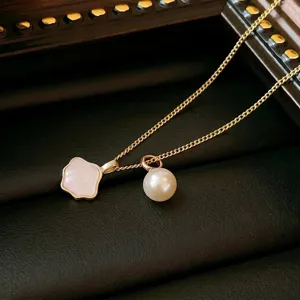 Detailed macro shot of a gold titanium necklace with white shell and pearl pendants