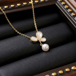 Close-up of elegant gold butterfly pendant necklace with pearl on black jewelry display