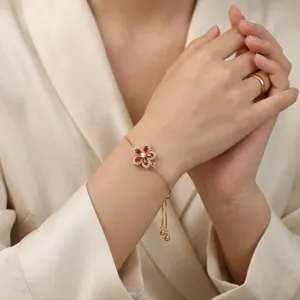 Gros plan d'un élégant bracelet doré réglable avec fleur rotative en cristal rouge