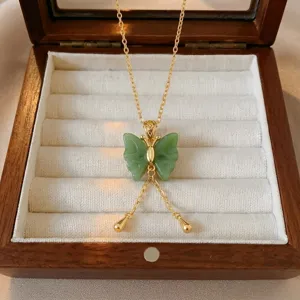 Primer plano de un collar de mariposa con jade de imitación verde y borlas doradas