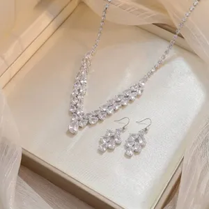 Close-up of sparkling zircon necklace and earrings set in a luxury cream jewelry box.