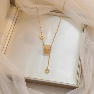 Detalle de elegante collar de oro con colgante cilíndrico de circonita en caja de regalo.
