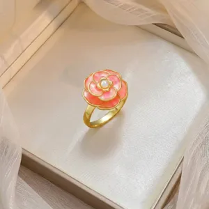 Macro view of a camellia flower ring with pink gradient petals and a center pearl