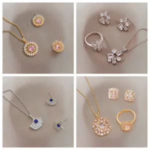 Four delicate titanium steel jewelry sets with colorful zircons on a soft grey surface.