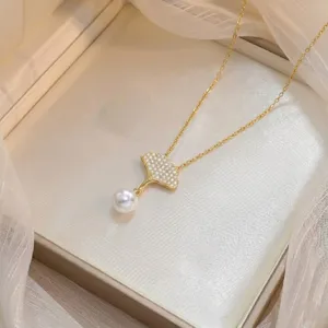 Detailed view of elegant gold ginkgo leaf pendant necklace with zircon pavé and white pearl