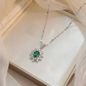 Close-up of elegant silver necklace with emerald green gemstone pendant on white gauze