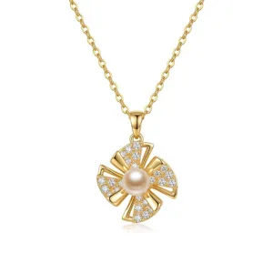 Detailed macro shot of a gold rotating four-leaf flower pendant with pearl and zircons