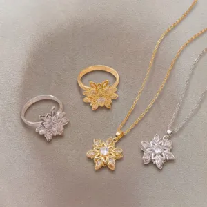 Detailed view of gold and silver flower rings and necklaces on fabric background.